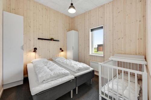 a bedroom with a bed and a crib in it at Lalandia Søndervig in Søndervig