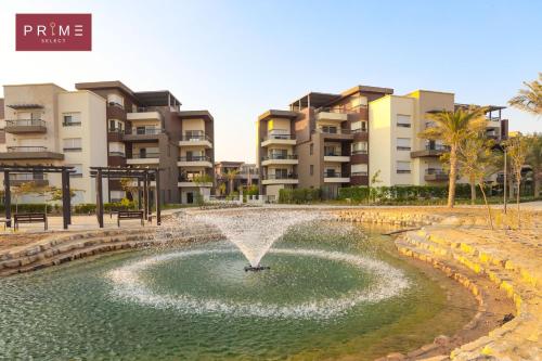 a fountain in a pond in front of condos at Prime Select New Giza in Giza