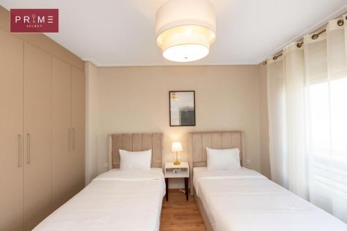 two beds in a room with a table and a window at Prime Select New Giza in Giza