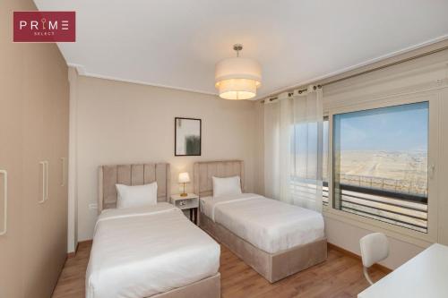 two beds in a room with a view of the desert at Prime Select New Giza in Giza