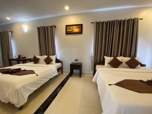a hotel room with two beds and curtains at The Moon Kampot Boutique in Kampot