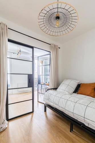 une chambre avec un lit blanc et une grande fenêtre dans l'établissement IMHOST - Appartement luxueux climatisé -Marseille -Le Panier, à Marseille