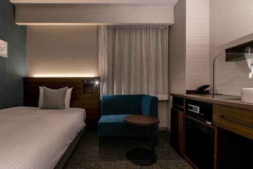 a hotel room with a bed and a chair at Hotel Vista Matsuyama in Matsuyama