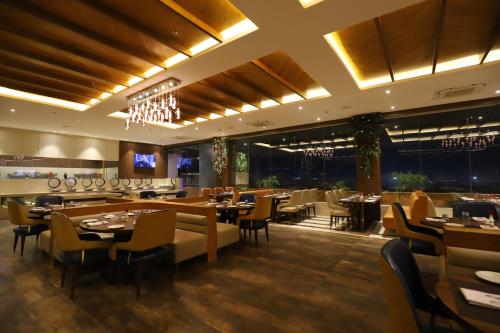 a restaurant with tables and chairs and a bar at The Pristine Hotel in Kānpur
