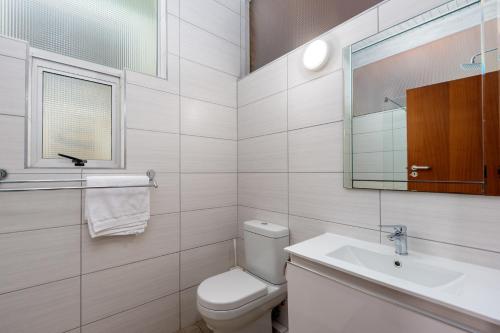 a white bathroom with a toilet and a sink at Vic Bay Beach House in Victoria Bay