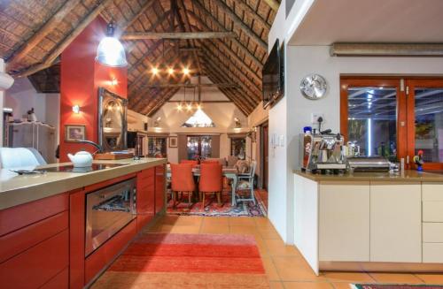 a large kitchen with red cabinets and a dining area at Lipizzaner Lodge in Kyalami
