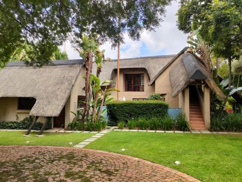 a house with a thatched roof and a yard at Lipizzaner Lodge in Kyalami