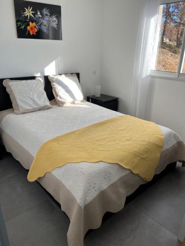 a bedroom with a large bed with a yellow blanket at Lac et Montagne in Chorges