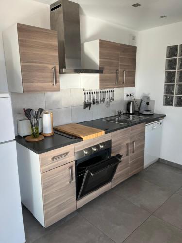 La cuisine est équipée d'armoires en bois et d'un four noir. dans l'établissement Lac et Montagne, à Chorges