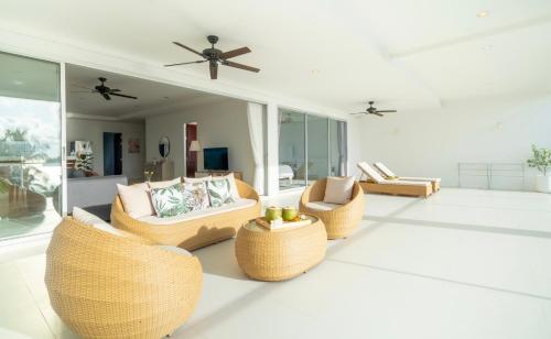 a living room with couches and tables and windows at Kata Seaview Jacuzzi Suite - Pasifora in Kata Beach