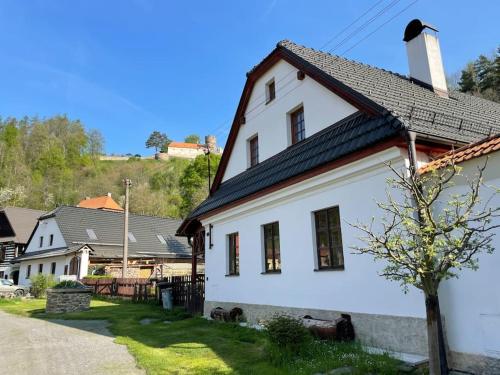 ein weißes Haus mit schwarzem Dach in der Unterkunft Chaloupka pod hradem in Svojanov