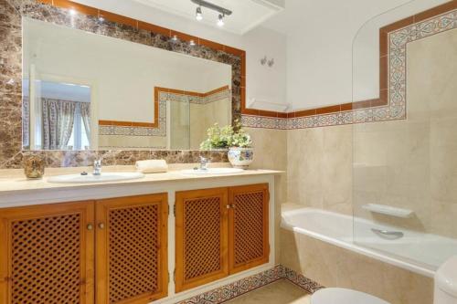 Santa Fe de los Boliches的住宿－Puebla Aida, Mijas Golf，带浴缸、水槽和镜子的浴室