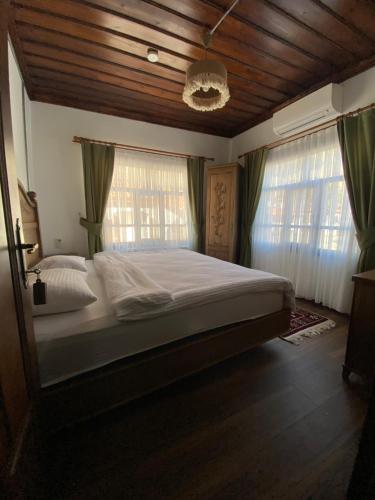 a bedroom with a large bed and two windows at Ziyagil Konağı in Amasya