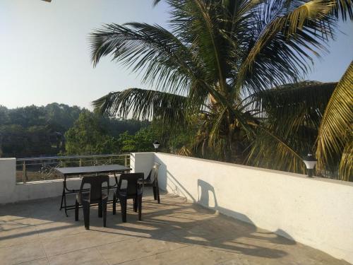 a table and chairs on a balcony with a palm tree at Swapnapurti Homestay in Alibaug
