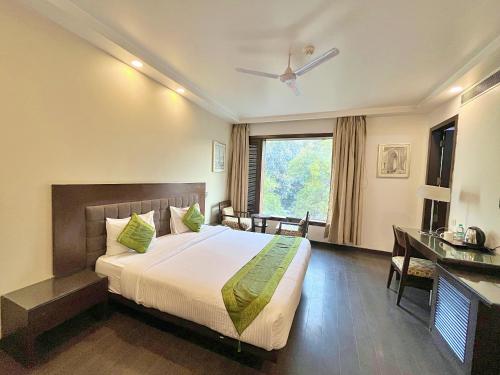 a bedroom with a bed and a desk and a window at Amber Inn by Orion Hotels in New Delhi