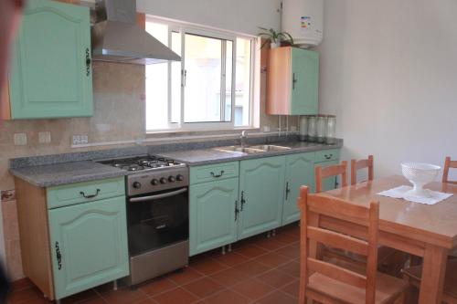 uma cozinha com armrios verdes, um lavatrio e um fogo em Quartos em vivenda serra da Estrela em Celorico da Beira