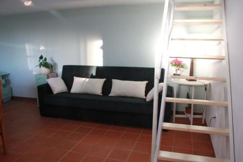 a living room with a black couch with white pillows at Quartos em vivenda serra da Estrela in Celorico da Beira