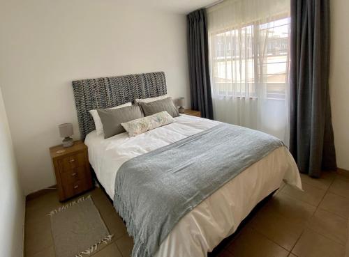 Un dormitorio con una cama grande y una ventana en Moringa Gardens Self Catering Apartments en Swakopmund