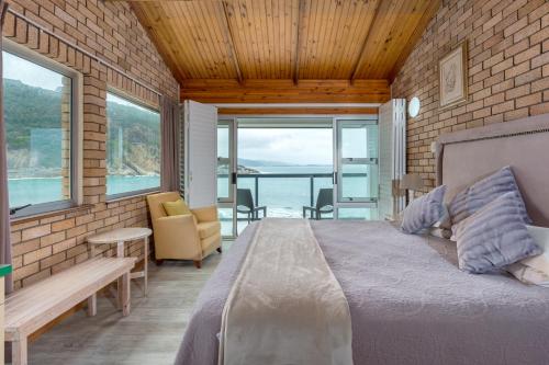 a bedroom with a bed and a view of the ocean at Vic Bay Beach House in Victoria Bay