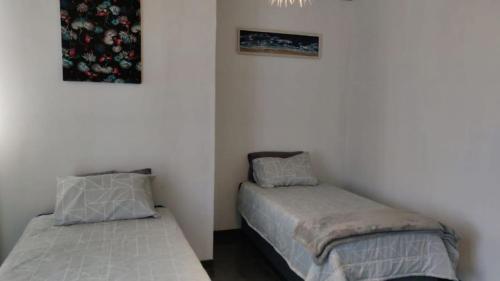1 dormitorio con 2 camas y 2 cuadros en la pared en Whalers Retreat, en Bettyʼs Bay