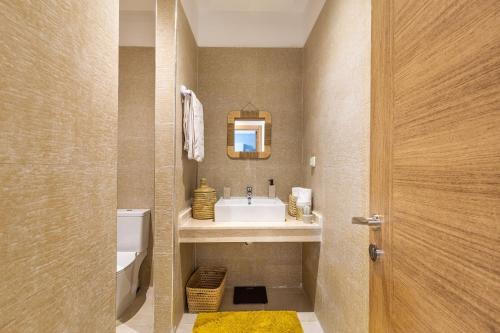 ein Badezimmer mit einem Waschbecken, einem WC und einem Spiegel in der Unterkunft Superbe Appart en Résidence Sécurisée avec piscine in Marrakesch