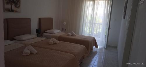 two beds in a hotel room with a window at Lemonis House in Nea Skioni