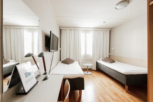 a hotel room with two beds and a desk at Hotel Jokipuisto in Kotka