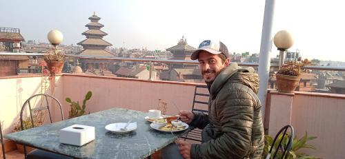 a man sitting at a table with a plate of food at HOTEL RUPAKOT AND ROOFTOP RESTAURANT in Bhaktapur