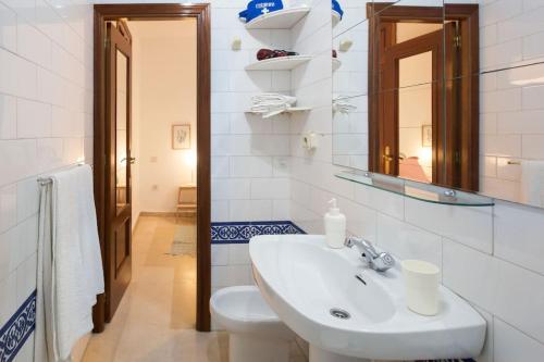 łazienka z umywalką, toaletą i lustrem w obiekcie Triana, cozy y con una ubicación ideal w Sewilli