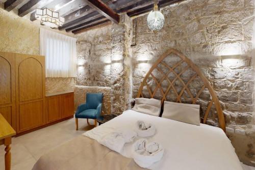 a bedroom with a large white bed and a stone wall at The house in the Ramchal in Acre