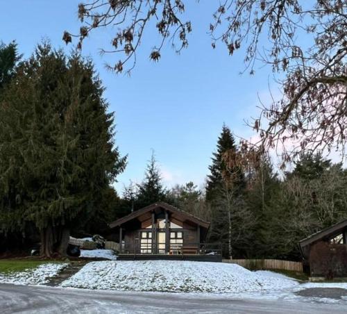 a house with snow on the ground in front of it at Bell Rock Holiday Lodge in Killin