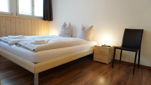 a bedroom with a bed with a chair and a table at Ufem Egg Ferienwohnungen in Innertkirchen