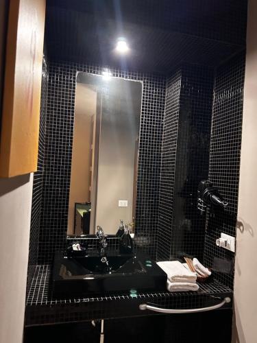 a black tiled bathroom with a sink and a mirror at LU Suites in Turin