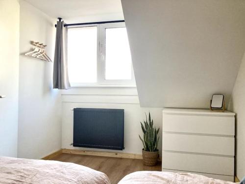 een slaapkamer met een bed, een raam en een radiator bij Cosy beach house for ocean & nature lovers in Noordwijk
