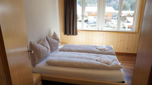 a bed sitting in a room with a window at Ufem Egg Ferienwohnungen in Innertkirchen
