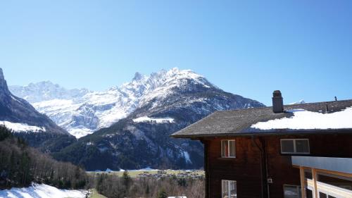 a house with snow covered mountains in the background at Ufem Egg Ferienwohnungen in Innertkirchen