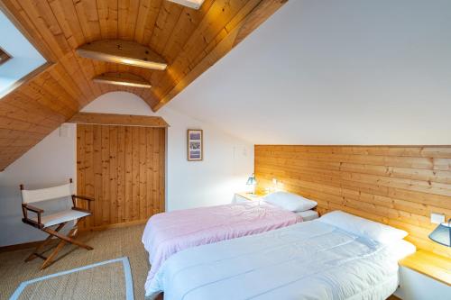 two beds in a bedroom with a wooden ceiling at Pont L'Abbé, maison avec jardin pour 4 in Pont-lʼAbbé