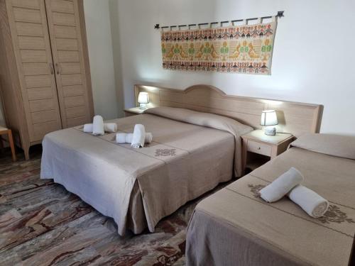 a hotel room with two beds and two tables at Hotel Plammas in Santa Maria Navarrese