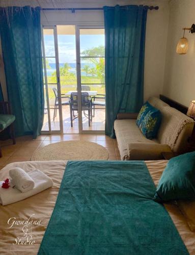 a bedroom with a bed and a living room with a patio at Accès Direct Plage, Vue Mer d'exception, Les Gwada Studios, Village Vacances in Sainte-Anne