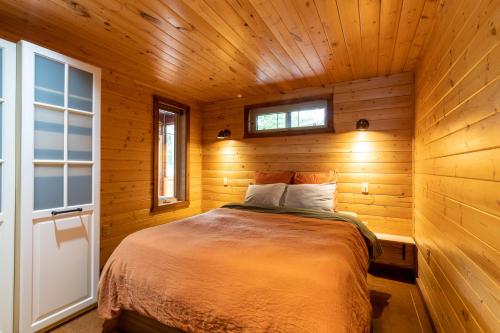 1 dormitorio con 1 cama en una cabaña de madera en The Qu INN - Cozy Cabin, en Parson