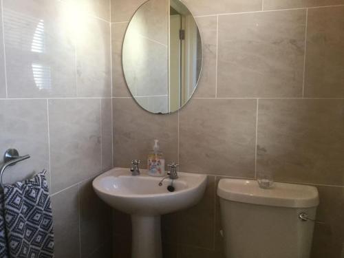ein Badezimmer mit einem Waschbecken, einem WC und einem Spiegel in der Unterkunft Home On The Edge Of Ireland! in Belmullet