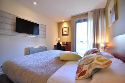 a bedroom with a bed with a television on the wall at Hôtel du Golf Saint Lazare in Limoges