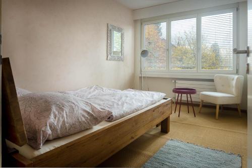 a bedroom with a bed and a chair and a window at Luxury apartment with terrace and garden free parking smart TV etc in St. Gallen