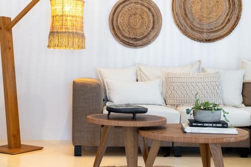 a living room with a couch and two tables at Amalgam Homes Paros in Ambelas