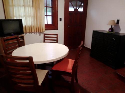 a room with a table and chairs and a television at Cabañas El Maiten in San Clemente del Tuyú