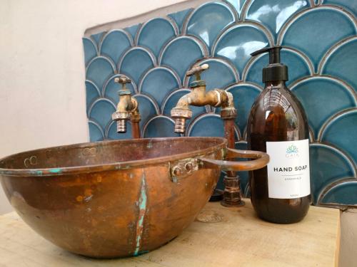 an old copper bowl and two bottles of wine on a table at Gaia A-frame cabin in Swellendam
