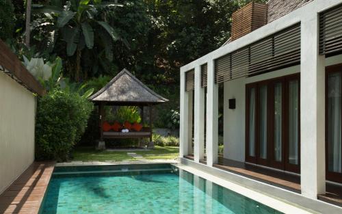 a swimming pool next to a house with a gazebo at The Samaya Ubud in Ubud