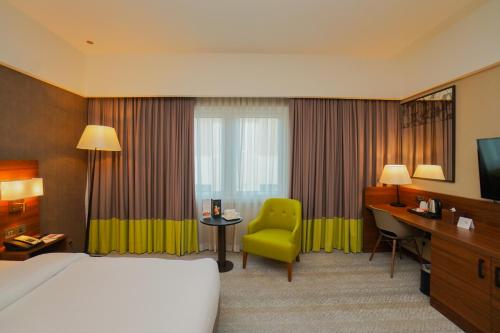 una camera d'albergo con letto, scrivania e sedia di The Grand Lux Hotel a Doha