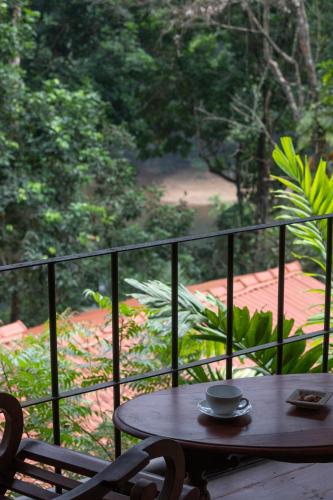 a table and chairs on a balcony with a view of a garden at Kuru Ganga Villa in Eratnagoda