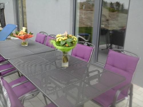 a table with purple chairs and a vase with flowers on it at B&B V.K. PGmbH in Saint-Vith